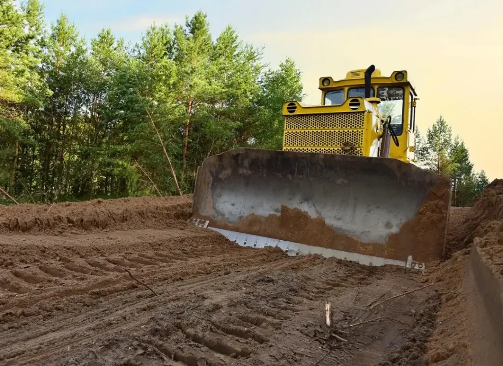 Yellow bulldozer clearing dirt.